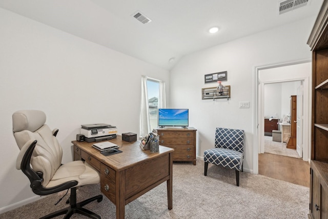 office space featuring visible vents, vaulted ceiling, light carpet, and baseboards