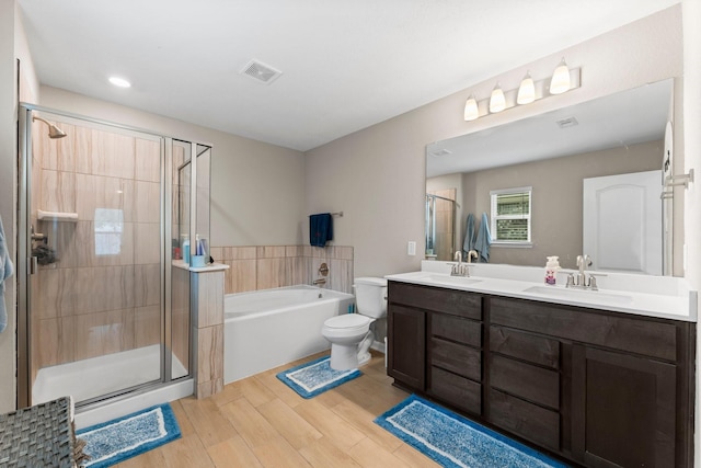 bathroom featuring wood finished floors, a sink, visible vents, and a shower stall