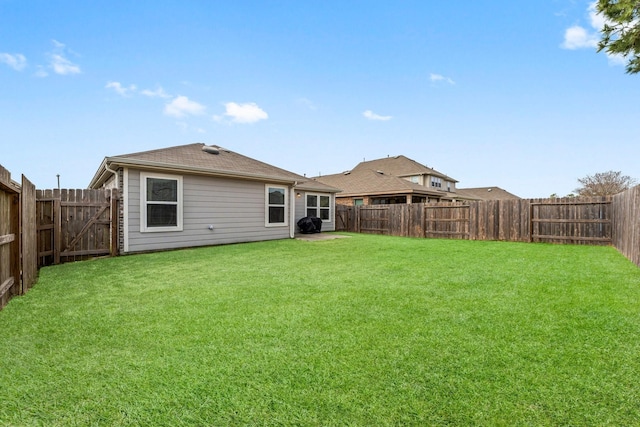 rear view of house with a fenced backyard and a yard