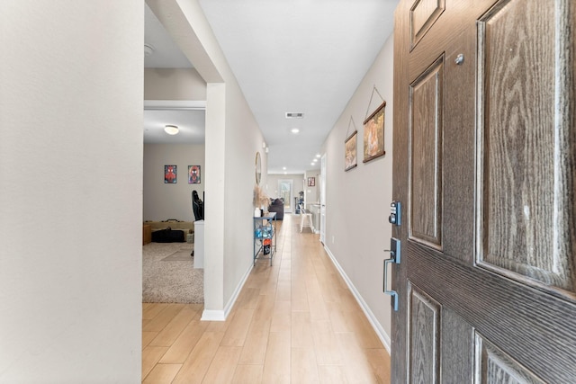 entryway with light wood finished floors, visible vents, and baseboards