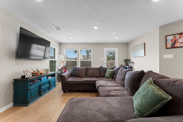 living room with light wood finished floors, baseboards, visible vents, a textured ceiling, and recessed lighting