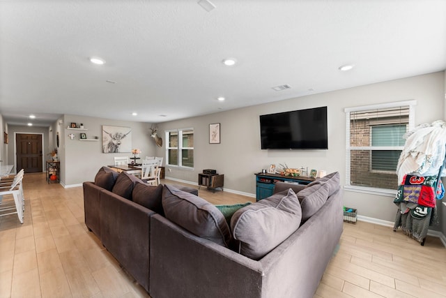 living room with baseboards, visible vents, light wood-style flooring, and recessed lighting