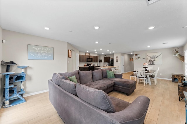 living room featuring light wood-type flooring, baseboards, and recessed lighting