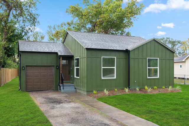 view of front of property with an attached garage, driveway, roof with shingles, a front lawn, and board and batten siding