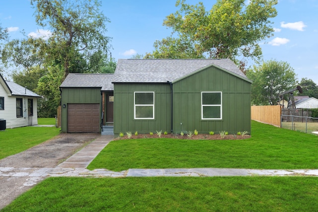 view of front of home featuring an attached garage, fence, roof with shingles, board and batten siding, and a front yard