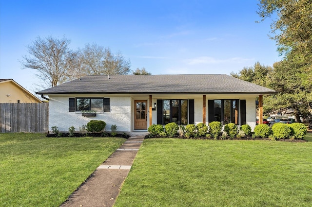 view of front facade featuring a front yard, fence, and brick siding