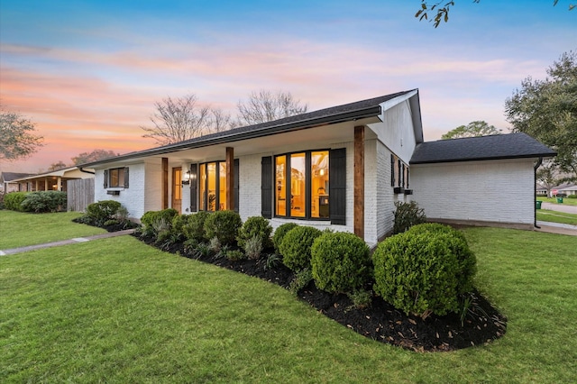 ranch-style home featuring a yard and brick siding