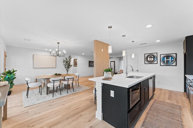 kitchen featuring light countertops, wall oven, a sink, and light wood-style flooring