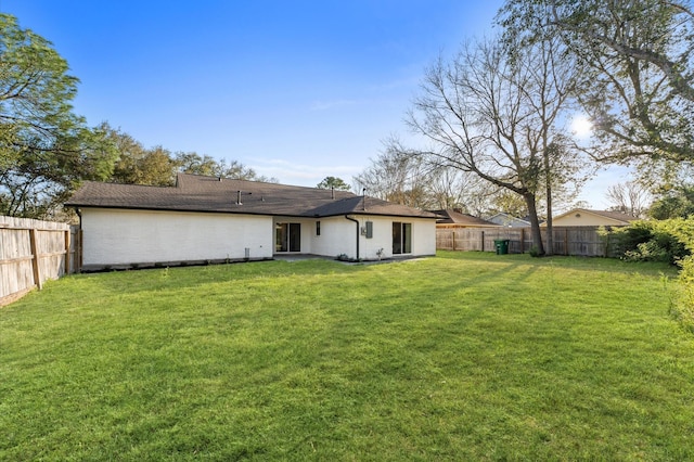 back of property featuring a fenced backyard and a yard