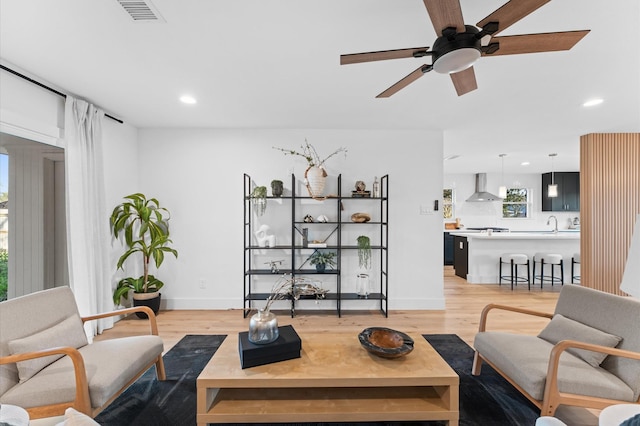 living room with light wood-style floors, visible vents, and recessed lighting