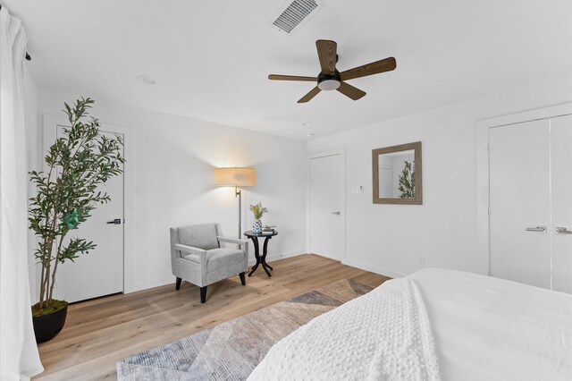 bedroom with a ceiling fan, wood finished floors, visible vents, and baseboards