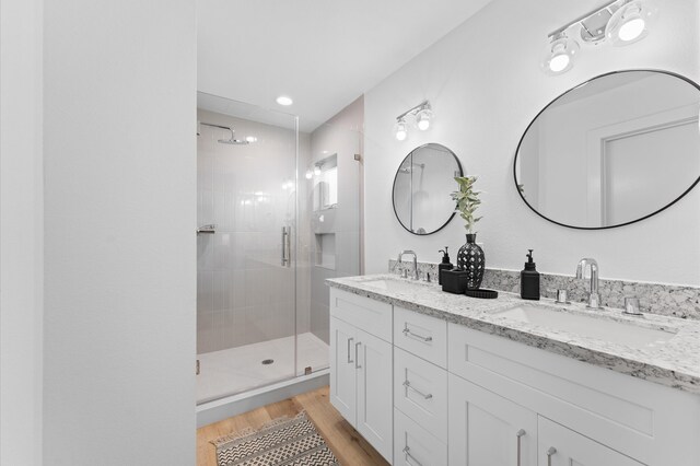 bathroom featuring a stall shower, a sink, and wood finished floors