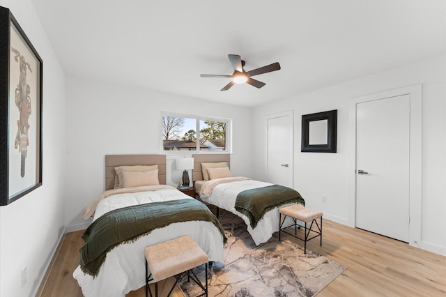 bedroom with light wood-style floors, ceiling fan, and baseboards