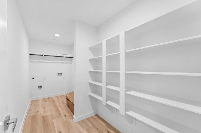 interior space with hookup for a washing machine, hookup for an electric dryer, laundry area, baseboards, and light wood-style floors