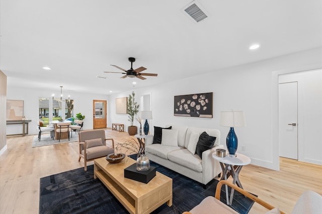 living area with recessed lighting, visible vents, wood finished floors, baseboards, and ceiling fan with notable chandelier