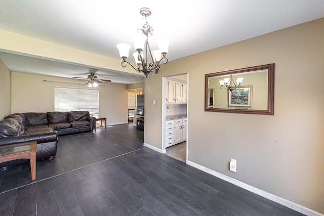 unfurnished living room featuring ceiling fan with notable chandelier, dark wood-style flooring, and baseboards