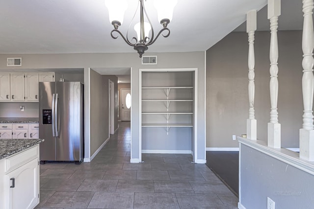 kitchen with white cabinets, stainless steel fridge with ice dispenser, visible vents, and baseboards