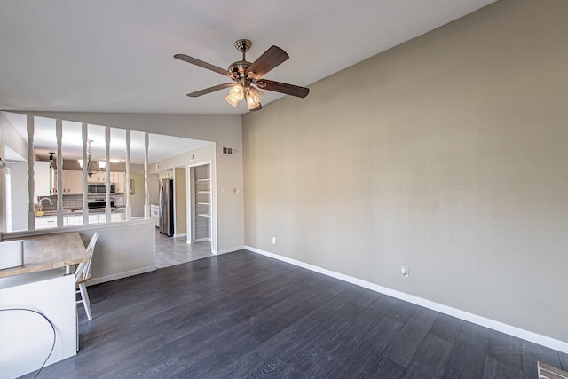 kitchen featuring dark wood finished floors, a peninsula, lofted ceiling, stainless steel appliances, and light countertops