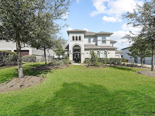 mediterranean / spanish-style house featuring an attached garage, stucco siding, fence, and a front lawn