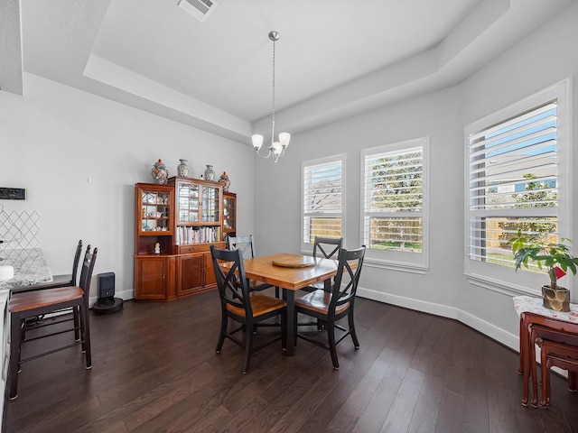 dining area with visible vents, dark wood-type flooring, baseboards, an inviting chandelier, and a raised ceiling