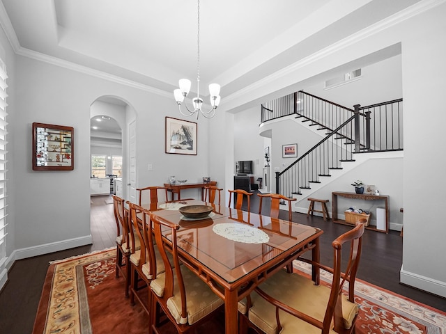 dining space featuring stairs, a raised ceiling, wood finished floors, and arched walkways