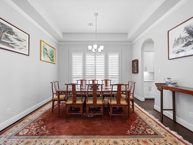 dining space featuring baseboards, a tray ceiling, arched walkways, and visible vents