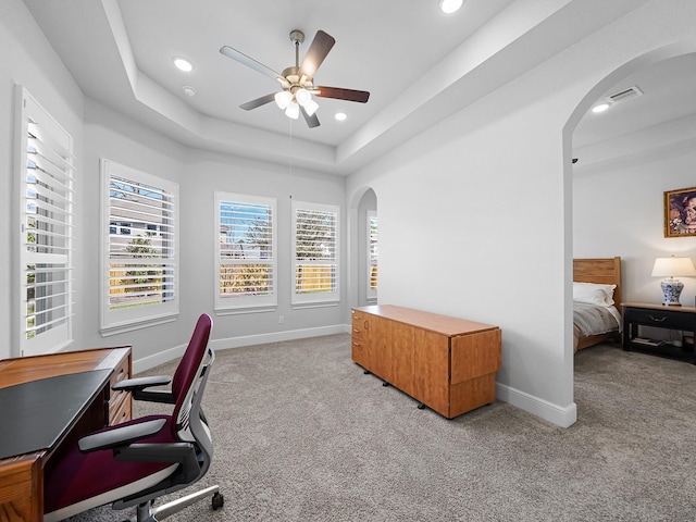 office with arched walkways, plenty of natural light, light carpet, and ceiling fan