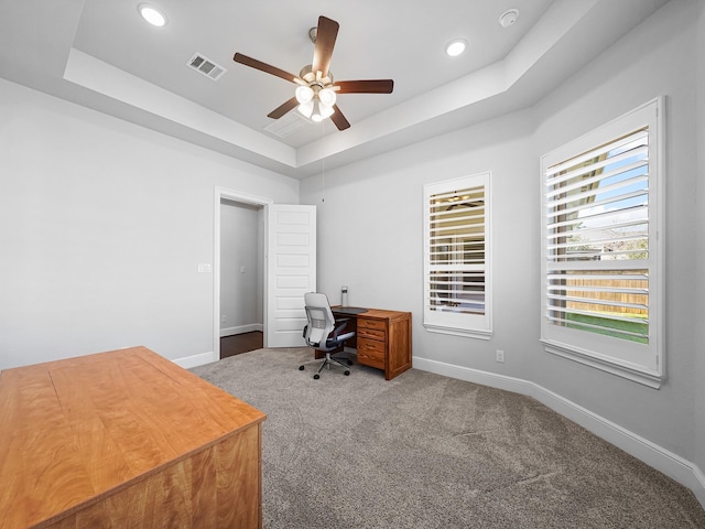 office space featuring a tray ceiling, baseboards, visible vents, and ceiling fan