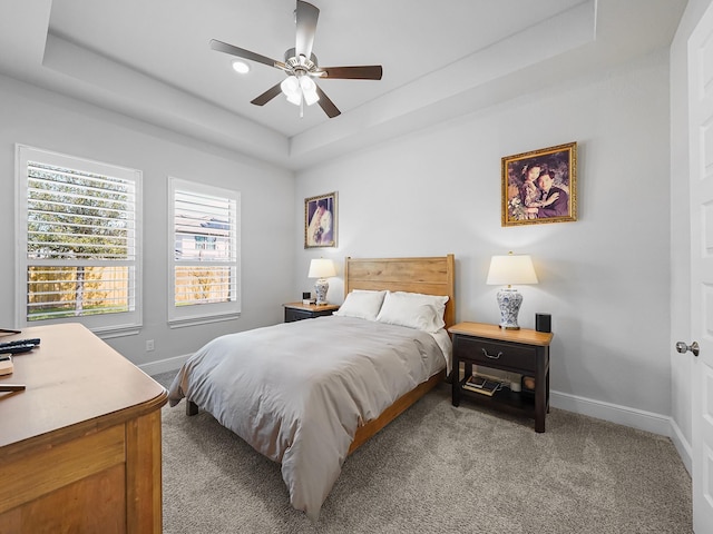 bedroom with light colored carpet, a raised ceiling, baseboards, and ceiling fan