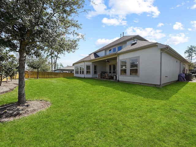 back of property featuring fence, central air condition unit, stucco siding, a yard, and a ceiling fan