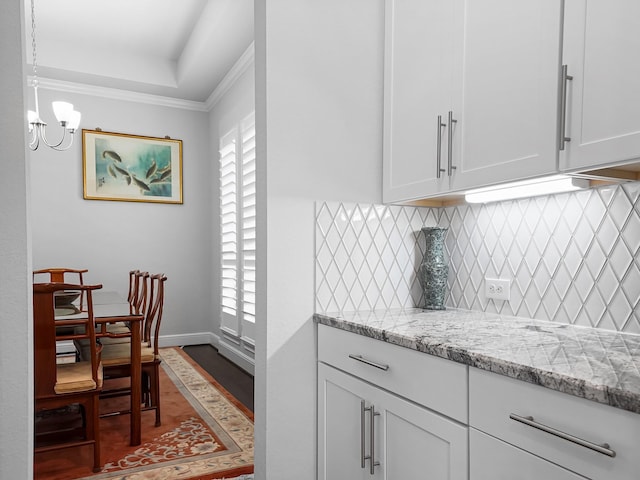 kitchen featuring a notable chandelier, light stone countertops, tasteful backsplash, and white cabinets