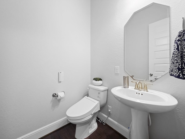 bathroom with toilet, wood finished floors, and baseboards