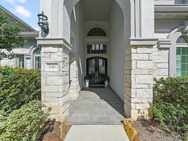 doorway to property featuring french doors, stone siding, and stucco siding