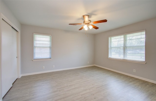 unfurnished room with light wood-style floors, a wealth of natural light, baseboards, and a ceiling fan