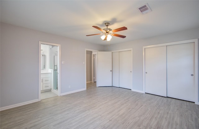 unfurnished bedroom featuring baseboards, visible vents, two closets, and wood finished floors