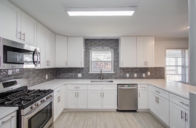 kitchen with stainless steel appliances, tasteful backsplash, a sink, and white cabinets