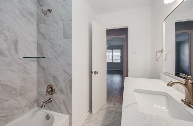 full bath with marble finish floor, a sink, washtub / shower combination, and baseboards