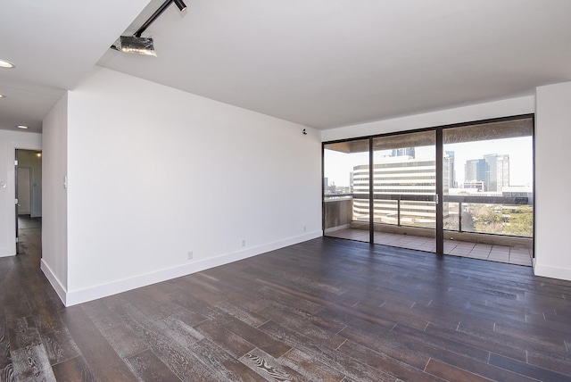 unfurnished room featuring a city view, recessed lighting, wood finished floors, and baseboards