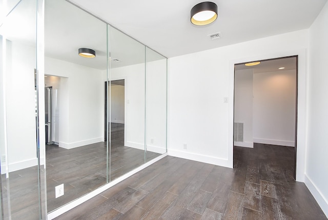 unfurnished bedroom featuring a closet, wood finished floors, and visible vents