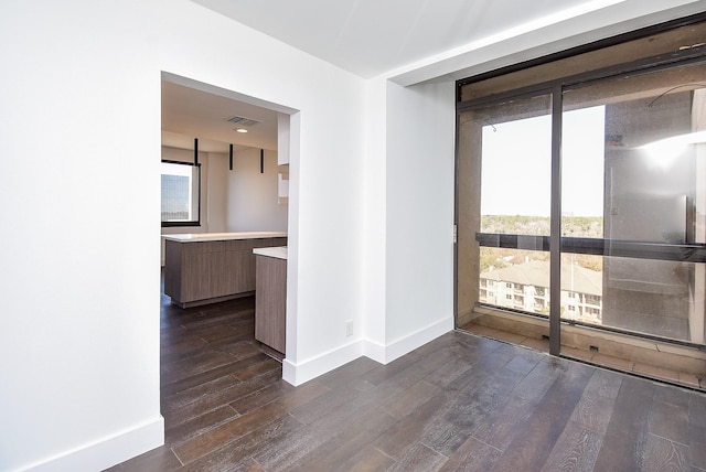 unfurnished room with expansive windows, dark wood-type flooring, plenty of natural light, and baseboards