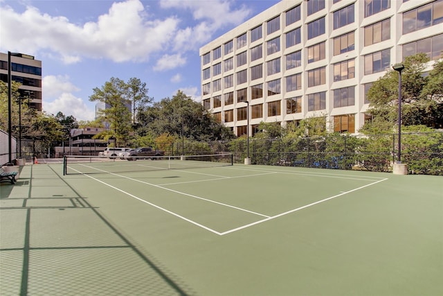 view of tennis court with community basketball court and fence