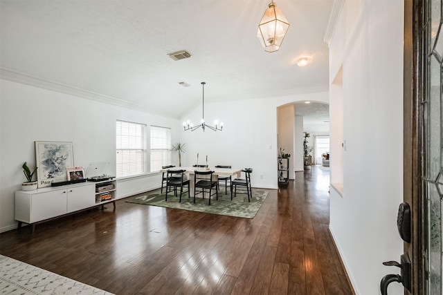 dining area with arched walkways, dark wood-style flooring, visible vents, baseboards, and crown molding