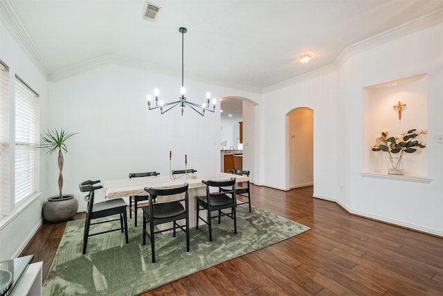 dining space with arched walkways, crown molding, dark wood finished floors, visible vents, and an inviting chandelier