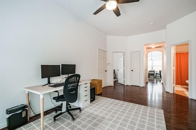 home office featuring a ceiling fan, baseboards, arched walkways, and wood finished floors