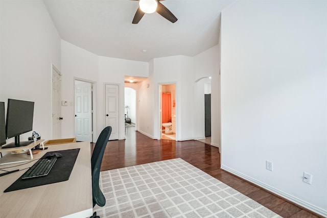 home office featuring baseboards, ceiling fan, arched walkways, and wood finished floors