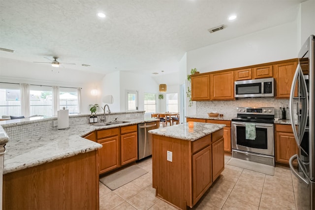 kitchen with visible vents, a center island, a sink, stainless steel appliances, and backsplash