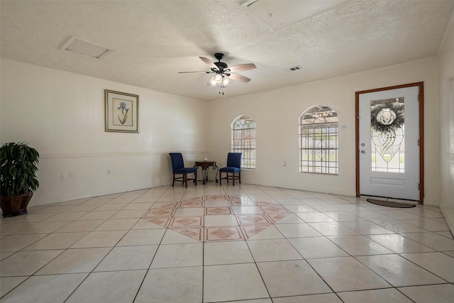 unfurnished office featuring visible vents, ceiling fan, a textured ceiling, and light tile patterned flooring