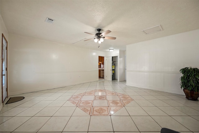 spare room with light tile patterned floors, a textured ceiling, visible vents, and a ceiling fan