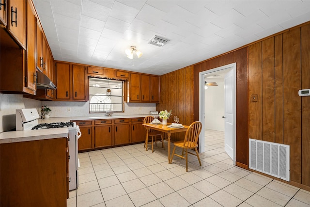 kitchen with white gas stove, brown cabinets, visible vents, and under cabinet range hood