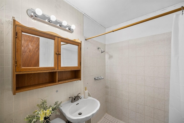 full bathroom featuring tiled shower, a sink, tile walls, and decorative backsplash